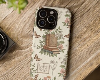 May include: A phone case with a cream background featuring a floral and book design. The design includes stacks of books, butterflies, and flowers in shades of pink, green, and brown. The case has a black camera module.