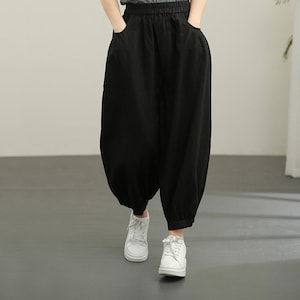 Könnte beinhalten: Schwarze, weite Hose mit lockerer, fließender Passform. Die Hose hat einen Kordelzugbund und Taschen an den Seiten.