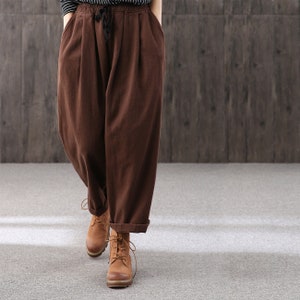 Puede incluir: Pantalón ancho marrón con cintura de cordón y dobladillo en los bajos. El pantalón está hecho de una tela suave y cómoda y es perfecto para el uso casual.