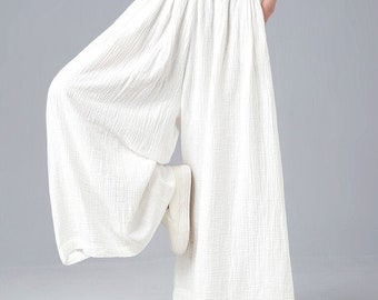 May include: White wide-leg pants with a loose, flowing fit. The pants have a high waist and are made of a lightweight, textured fabric.