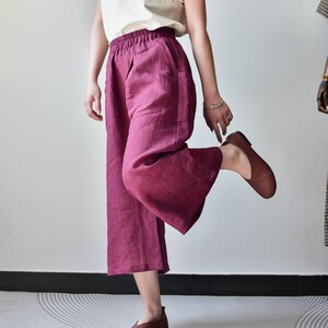Puede incluir: Una persona con una camiseta sin mangas color crema y pantalones anchos de color magenta. La persona tambi&eacute;n lleva zapatos de cuero marr&oacute;n. Los pantalones tienen bolsillos y cintura el&aacute;stica. El atuendo es informal y c&oacute;modo.