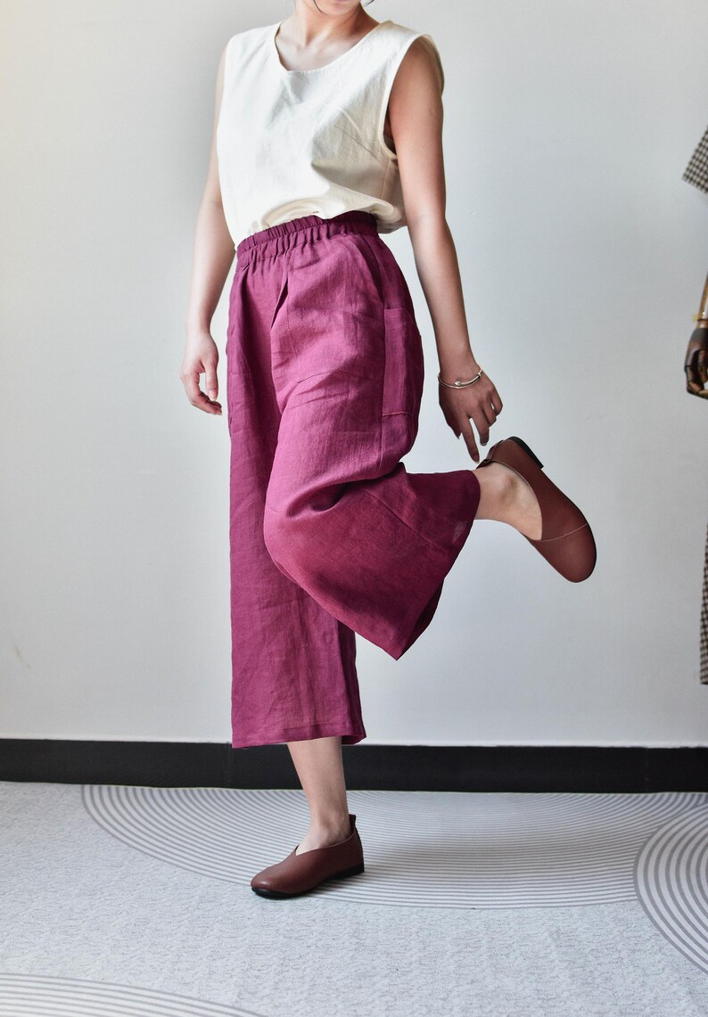 Puede incluir: Una persona con una camiseta sin mangas color crema y pantalones anchos de color magenta. La persona tambi&eacute;n lleva zapatos de cuero marr&oacute;n. Los pantalones tienen bolsillos y cintura el&aacute;stica. El atuendo es informal y c&oacute;modo.