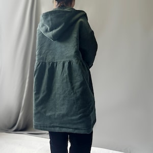 May include: A dark green corduroy hooded jacket with a cinched waist and long sleeves.
