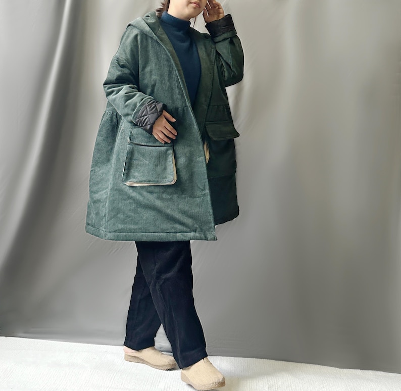 May include: A green corduroy jacket with a hood and large pockets. The jacket has a quilted lining and a contrasting fabric trim.