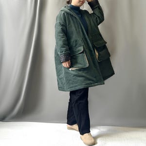 May include: A long, green corduroy coat with a hood and large pockets. The coat has a contrasting black and white lining on the sleeves and pockets.