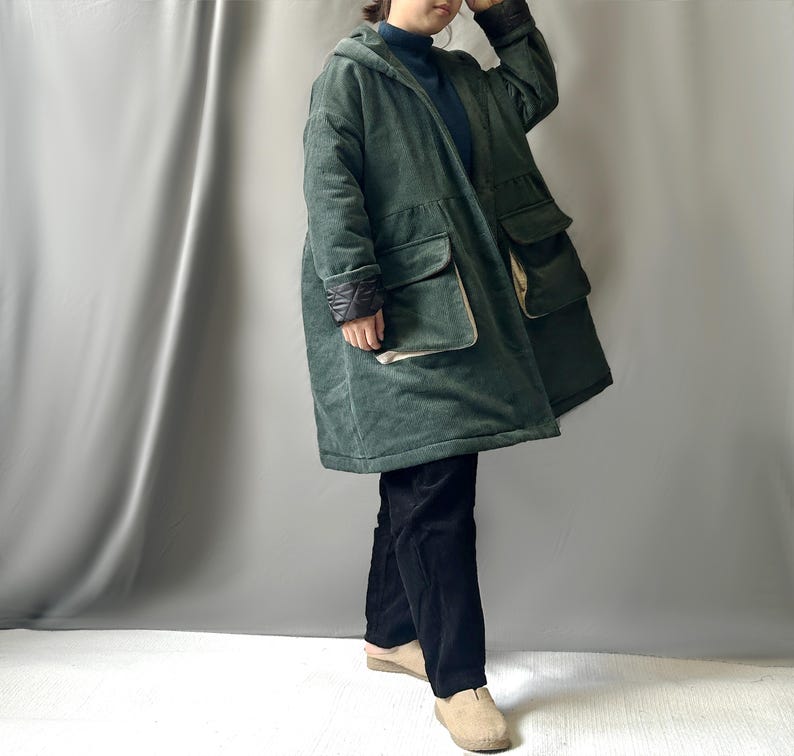 May include: A long, green corduroy coat with a hood and large pockets. The coat has a contrasting black and white lining on the sleeves and pockets.
