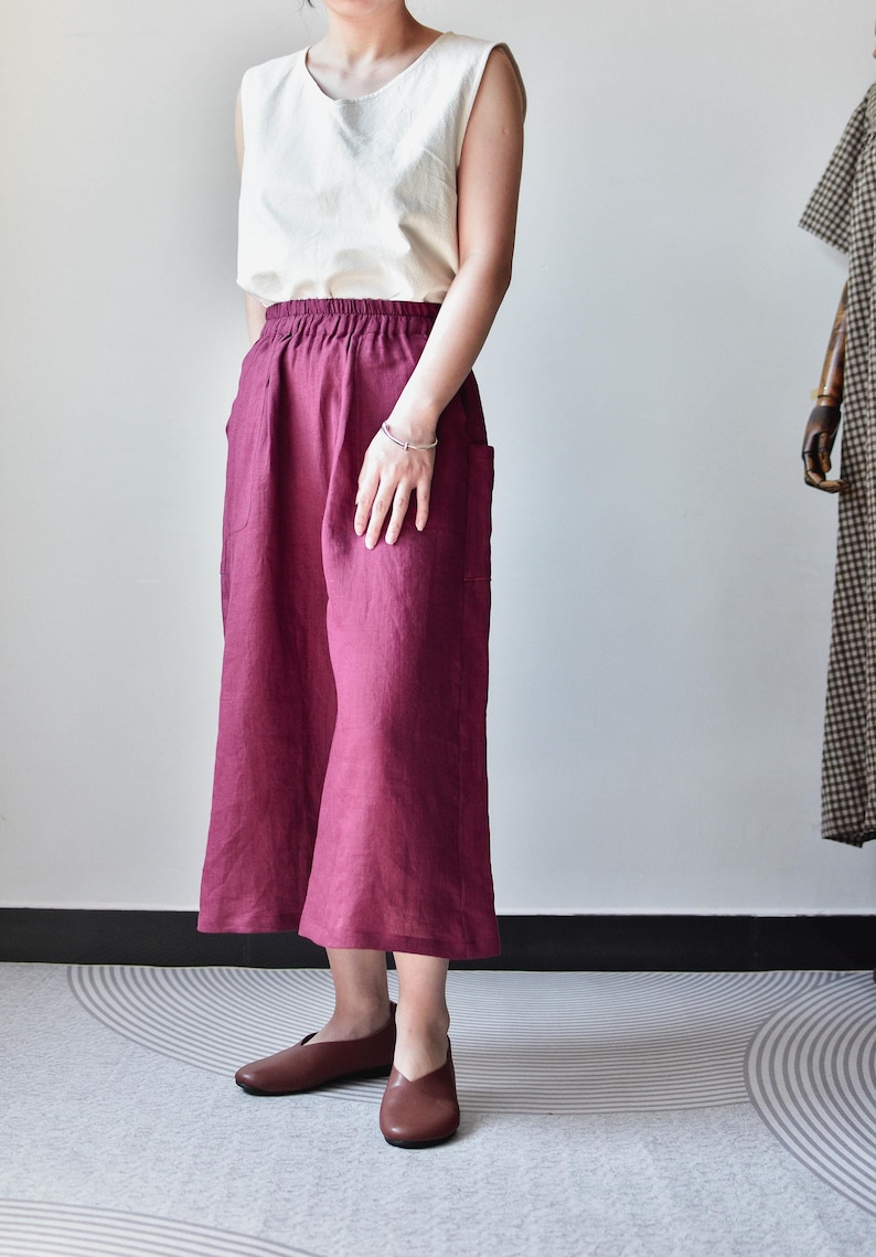 Puede incluir: Una camiseta sin mangas color crema combinada con pantalones anchos burdeos. Los pantalones tienen bolsillos y una c&oacute;moda cintura el&aacute;stica. Los zapatos planos de cuero marr&oacute;n completan el conjunto, creando un look relajado y cotidiano.