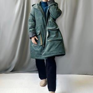 May include: A long, green corduroy coat with a hood and large pockets. The coat has a button closure and a quilted lining.