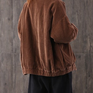 May include: A brown corduroy jacket with a zipper closure and a drawstring at the waist.
