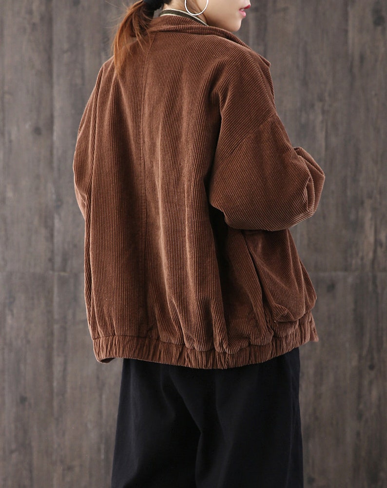 May include: A brown corduroy jacket with a zipper closure and a drawstring at the waist.