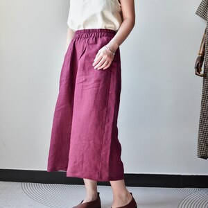 Puede incluir: Una camiseta sin mangas de color crema combinada con una falda burdeos de pernera ancha. La falda tiene cintura alta y bolsillos. Zapatos de cuero marr&oacute;n completan el conjunto. El conjunto es sencillo y elegante, adecuado para uso informal.