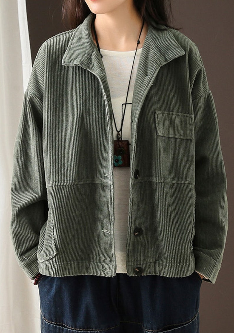 May include: A green corduroy jacket with a button fastening and a patch pocket on the left side. The jacket has a relaxed fit and a slightly cropped length.