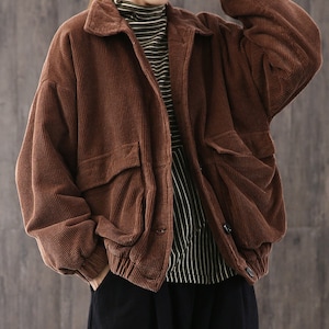 May include: A brown corduroy jacket with a button closure and large pockets. The jacket has a relaxed fit and a slightly oversized silhouette.