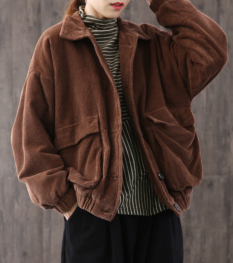 May include: A brown corduroy jacket with a button closure and large pockets. The jacket has a relaxed fit and a slightly oversized silhouette.
