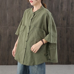 May include: A loose-fitting, green linen shirt with a button-up front and a collar. The shirt has a relaxed fit and a slightly oversized silhouette.