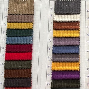 May include: A swatch card with 45 different fabric samples. The samples are arranged in rows and columns. The fabric is a corduroy material in a variety of colors, including red, blue, green, brown, and yellow.