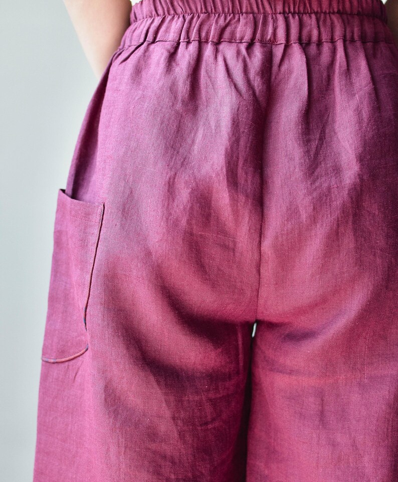 Puede incluir: Primer plano de un pantal&oacute;n de lino color magenta. El pantal&oacute;n tiene una cintura el&aacute;stica y un bolsillo en el lado izquierdo. La tela tiene un aspecto suave y texturizado.