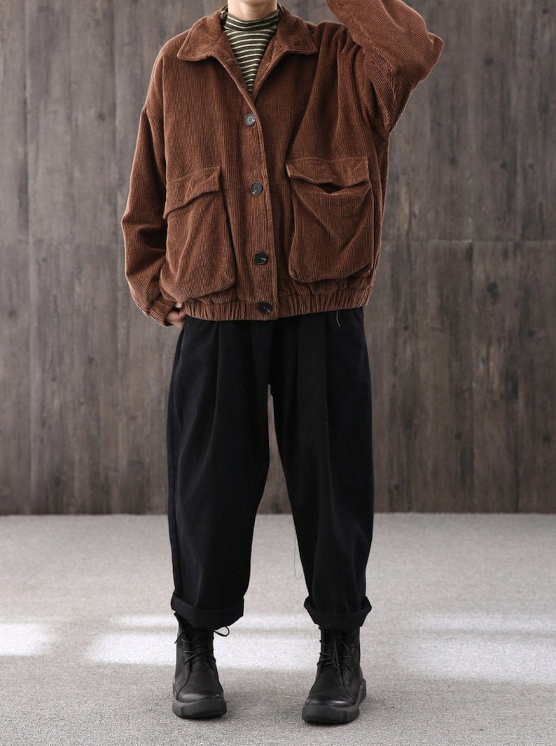 May include: A brown corduroy jacket with a button closure and two large patch pockets. The jacket has a relaxed fit and a slightly cropped length.