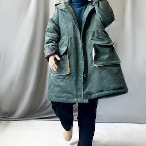 May include: A long, green corduroy coat with a hood and large pockets. The coat has a button closure and a relaxed fit.