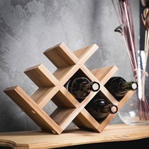Puede incluir: Estante de vino de madera con un dise&ntilde;o geom&eacute;trico, que puede contener seis botellas de vino. El estante est&aacute; hecho de madera natural y tiene un acabado r&uacute;stico.