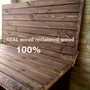 May include: A dark brown wooden panel with a hinged top. The panel is made of reclaimed wood and is 100% real wood. The panel is attached to a wall with a brick pattern.