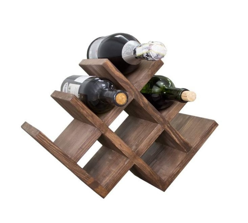 Puede incluir: Un estante de vino de madera marr&oacute;n oscuro con un dise&ntilde;o de cruz que tiene capacidad para seis botellas de vino. Se pueden ver tres botellas en la imagen.