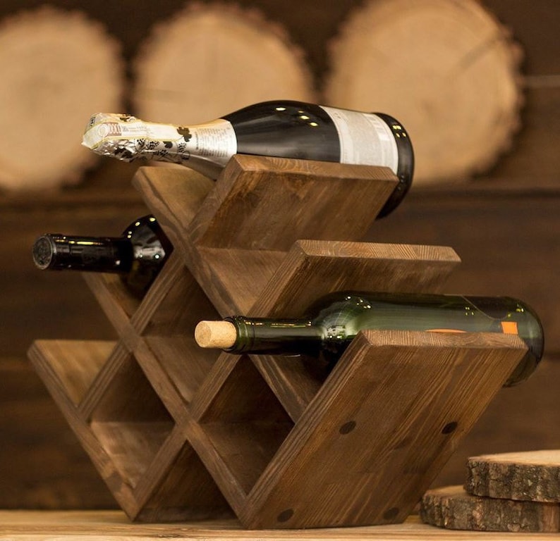 Puede incluir: Un estante de vino de madera con un tinte marr&oacute;n oscuro. El estante est&aacute; dise&ntilde;ado para contener seis botellas de vino. Hay dos botellas de vino en el estante, una es un vino tinto oscuro y la otra es un vino verde.