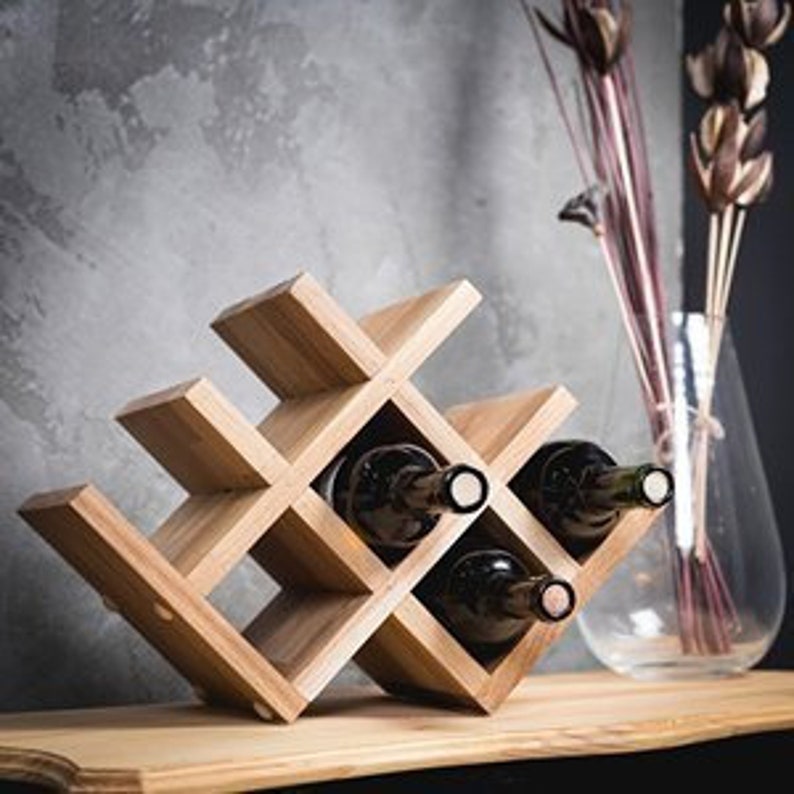 Puede incluir: Estante de vino de madera con un dise&ntilde;o geom&eacute;trico, que puede contener seis botellas de vino. El estante est&aacute; hecho de madera natural y tiene un acabado r&uacute;stico.