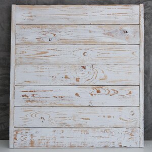May include: Whitewashed wooden sign with a distressed finish. The sign is made of horizontal planks of wood and has a rustic look.