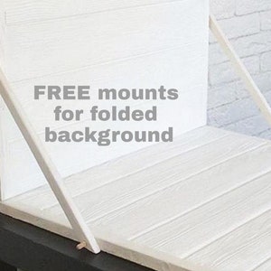 May include: A white wooden background with a folding design. The background is made of horizontal planks and supported by angled wooden supports. The text "FREE mounts for folded background" is visible.