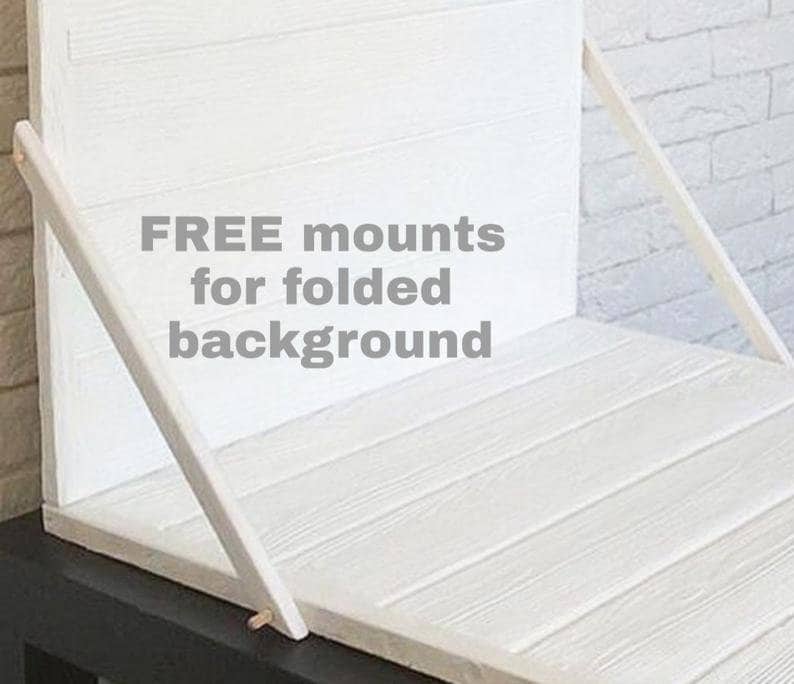 May include: A white wooden background with a folding design. The background is made of horizontal planks and supported by angled wooden supports. The text "FREE mounts for folded background" is visible.
