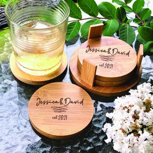 May include: Set of four bamboo coasters with a holder. The coasters are engraved with the text "Jessica & David est. 2021".