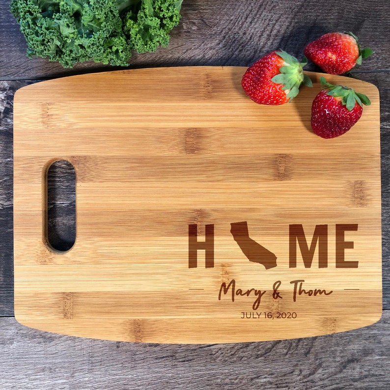May include: A brown bamboo chopping board with a handle and the words "HOME" with a silhouette of the state of California in place of the "O". The text "Mary & Thom" and "JULY 16, 2020" are also engraved on the board.