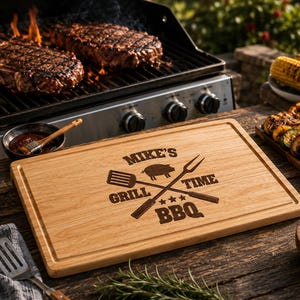 Peut inclure: Une planche à découper rectangulaire en bois avec une rainure à jus, gravée avec le texte MIKE'S GRILL TIME BBQ, une icône de cochon et des ustensiles de grillade croisés. La planche présente un grain de bois naturel sur une surface sombre.