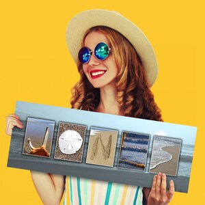 May include: A woman wearing a straw hat and sunglasses holds a sign with the word "JONI" spelled out using beach-themed images. The images include a seashell, a sand dollar, a wave, and a footprint in the sand.