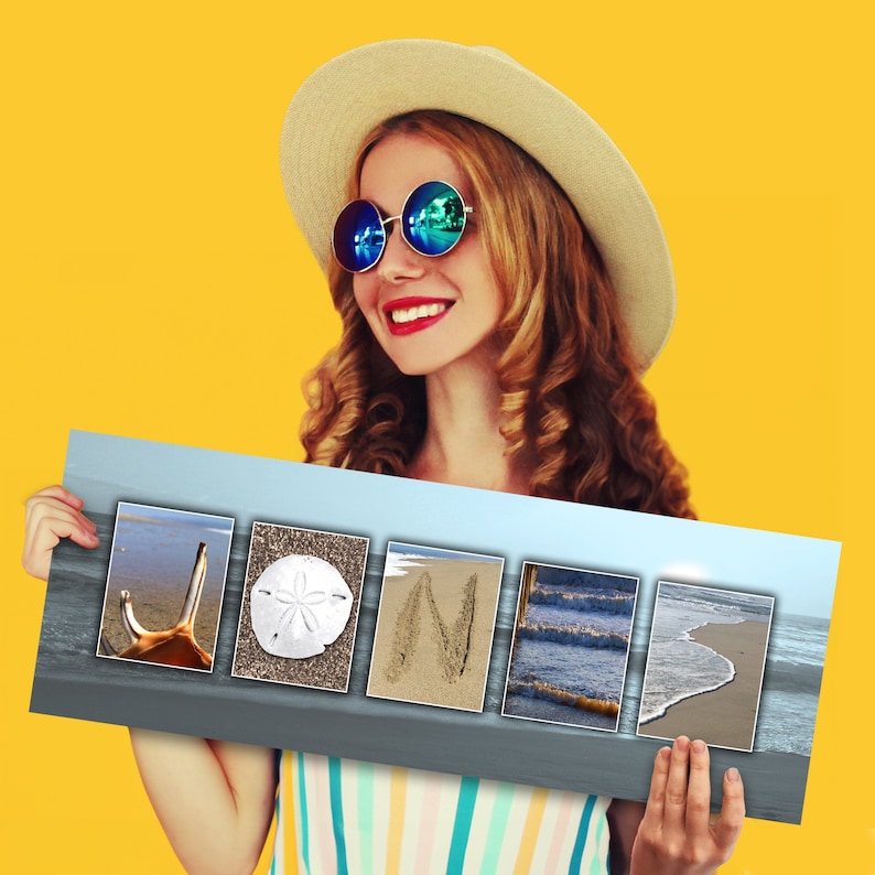 May include: A woman wearing a straw hat and sunglasses holds a sign with the word "JONI" spelled out using beach-themed images. The images include a seashell, a sand dollar, a wave, and a footprint in the sand.
