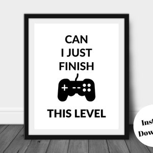Pu&ograve; includere: Stampa con cornice nera con la scritta "CAN I JUST FINISH THIS LEVEL" e una grafica di controller nera. La stampa &egrave; su sfondo bianco. Un adesivo rotondo "Instant Download" si trova nell'angolo in basso a destra.