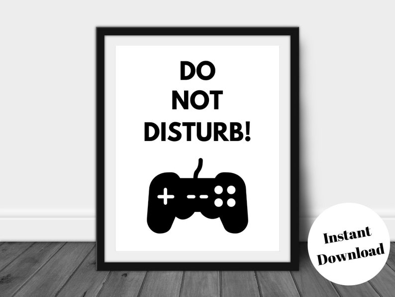 Pu&ograve; includere: Una stampa incorniciata con le parole "DO NOT DISTURB!" sopra una grafica nera di un controller di videogiochi. La stampa &egrave; in una cornice nera e ha uno sfondo bianco. Un adesivo circolare in basso a destra dice "Download istantaneo".