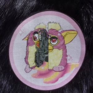 Puede incluir: Un juguete de peluche rosa y amarillo con un robot negro y gris en su interior. El juguete está sobre un fondo rosa y blanco con estrellas.