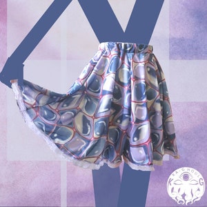 May include: A blue and purple patterned skirt with a white lace trim. The skirt has a geometric pattern of overlapping circles.