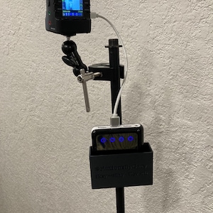 May include: A black camera with a screen is mounted on a tripod stand. A black power bank with blue lights is attached to the stand. The power bank is labeled "Solutions By Gary Easy-eBay-Favors".