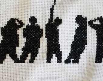 May include: Cross-stitch artwork featuring black silhouettes of people in various poses, spelling out the word "YOU". The figures are stitched on a white fabric background, creating a contrasting visual effect. The piece is handmade.