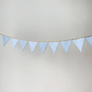 Op de afbeelding: Een slinger van driehoekige vlaggetjes met een lichtblauw en wit vichy-ruitpatroon. De stoffen wimpels zijn bevestigd aan een dun, naturelkleurig touw, waardoor een decoratieve banner ontstaat die geschikt is om op te hangen.