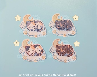 May include: Four stickers featuring cartoon cats sleeping on clouds with crescent moons and stars. The cats have different color patterns, including calico and brown tabby. The stickers have a subtle shimmery effect, with a light blue background.