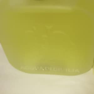 May include: A clear glass bottle with a gold cap and a white label that reads "Acqua di Sicilia".