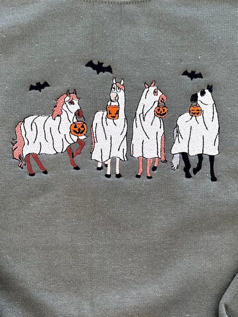 Op de afbeelding: Vier paarden verkleed als geesten voor Halloween, elk met een emmer met een pompoen. De paarden zijn roze en wit met zwarte hoeven en staan ​​op een groene achtergrond met vleermuizen die erboven vliegen.