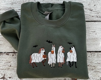 May include: A green sweatshirt with an embroidered design of four horses dressed as ghosts holding buckets of candy. The horses are wearing white sheets and have bats flying above them.