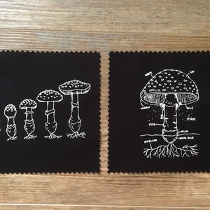 Peut inclure: Deux carrés de tissu noirs avec des illustrations de champignons blancs. L'un montre un schéma de champignon avec des étiquettes. L'autre affiche une série de champignons en croissance. Les illustrations sont de style dessiné à la main.
