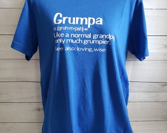 May include: A royal blue t-shirt with a white graphic that defines "Grumpa" as "like a normal grandpa, only much grumpier." The definition also includes the phonetic spelling of the word and the phrase "See also: loving, wise."
