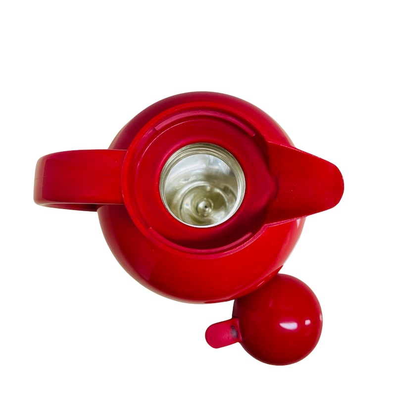 May include: A red thermos with a lid and a spout. The thermos has a silver interior and is made of metal.